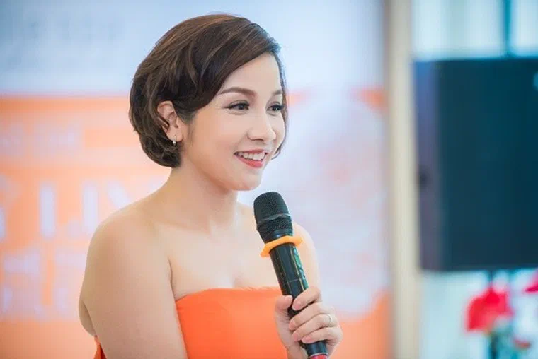 Mỹ Linh tóc ngắn nâu sáng, đỉnh chải phồng uốn sóng lệch, cầm micro