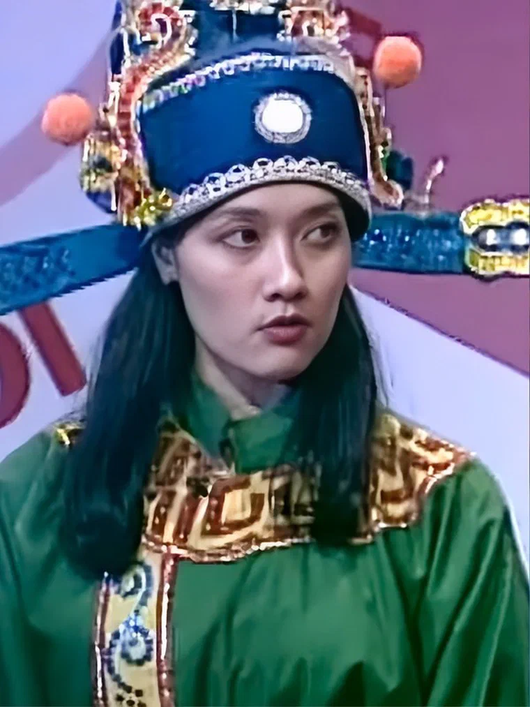 Vân Dung trong vai Táo Xã hội năm 2003, đội mũ Táo xanh viền vàng, áo bào xanh lá, tóc đen dài thẳng buông qua vai