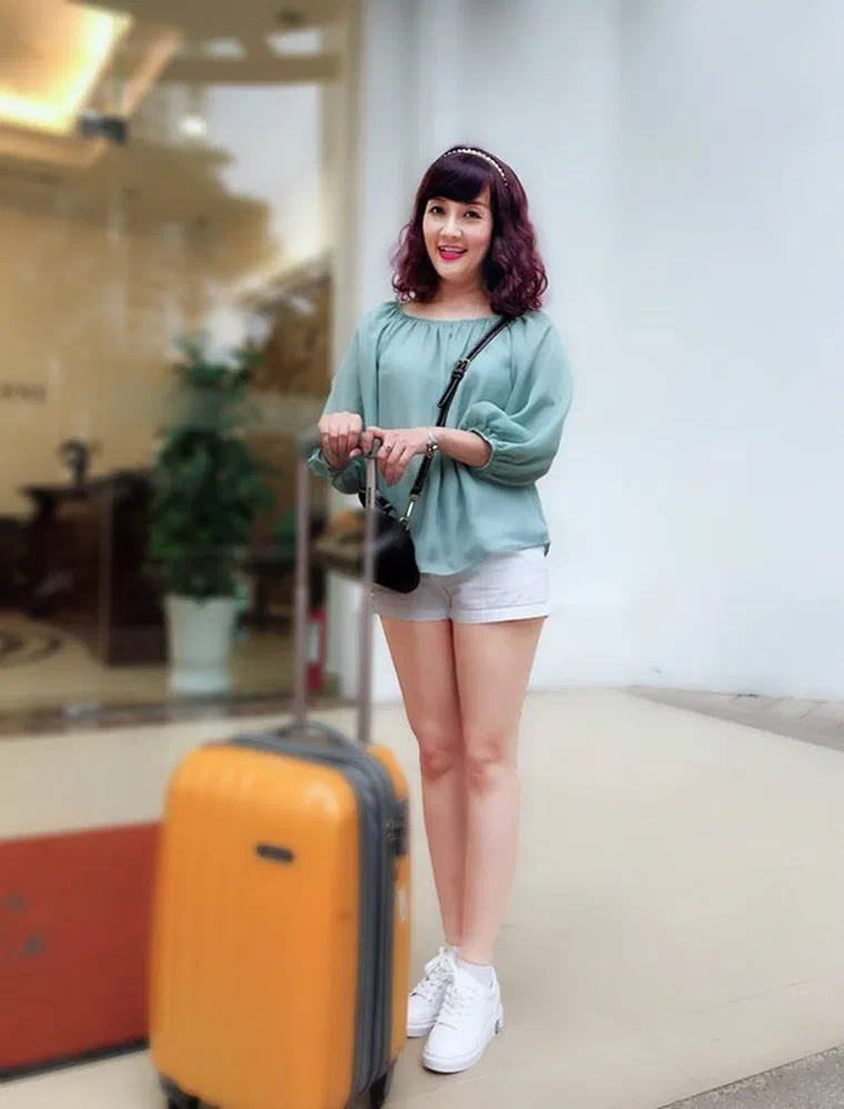 Vân Dung mặc áo xanh ngọc, quần soóc trắng, đeo cài tóc đính hạt, tóc nhuộm tím mận uốn sóng dài ngang vai, mái thưa